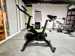 A stationary bike in a room with a mirrored wall, a door, and a shelf with items.
