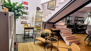 Un intérieur moderne avec un escalier, des meubles en osier et une bibliothèque.