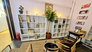 Un salon chaleureux avec une bibliothèque, une plante en pot, des meubles en osier et un extincteur.