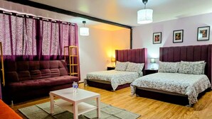 Une pièce comprenant un canapé, deux lits simples, une table basse et une lampe.