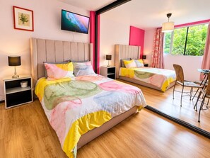 Ein Hotelzimmer mit zwei Betten, einem Fernseher, einem Fenster mit Vorhängen und einem Spiegel, der das Zimmer widerspiegelt.