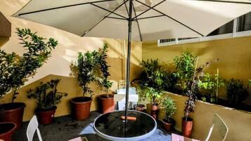 An outdoor patio with a round table and two chairs, surrounded by potted plants.