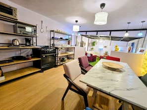 A modern kitchen with a marble countertop, a built-in oven, and a dining area with a red sofa and a table. - Suite Rosa Familiar 7personas Cocina baño centrica (Mexico City)
