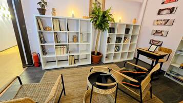 A cozy living room with wicker furniture, a bookshelf, and a potted plant.