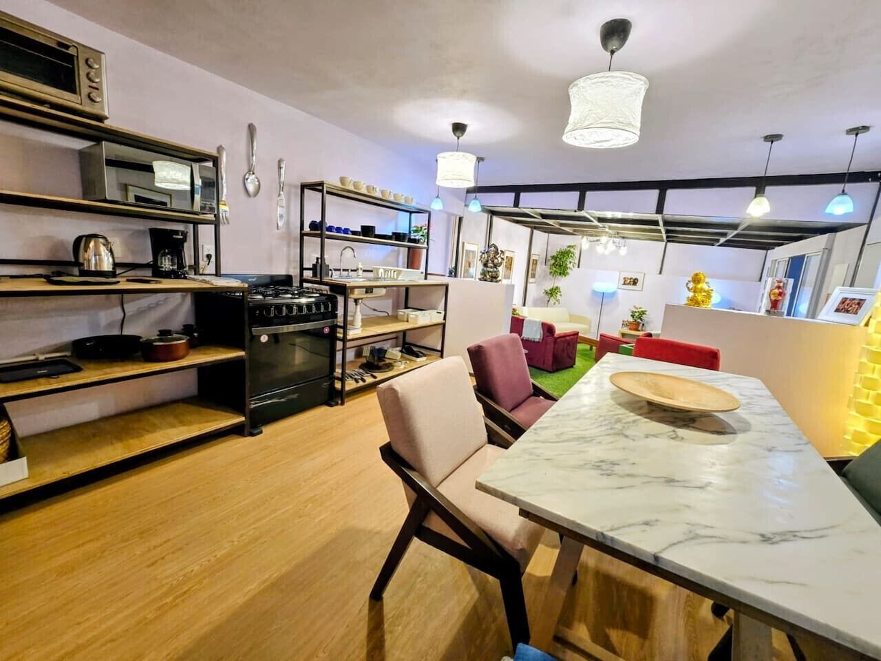 A modern kitchen with a marble countertop, a built-in oven, and a dining area with a red sofa and a wooden table.