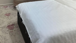 A bedroom with a bed, a sofa, an air conditioning unit, and a carpet with a floral pattern. - Palm Square MED (Madinah)