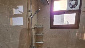 A bathroom with a toilet, shower, and a fan on the wall. - Palm Square MED (Madinah)
