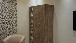 A bedroom with a bed, a wardrobe, a chair, and a patterned wall. - Palm Square MED (Madinah)