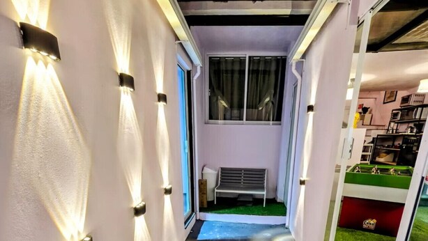A narrow hallway with artificial grass, a bench, and a door leading to a room with a green carpet. - Suite roja céntrica ideal para conocer la ciudad (Mexico City)