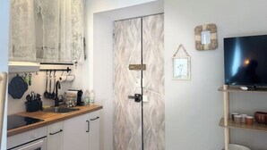 A compact kitchen with a wooden countertop, a sink, and a double door with a textured design. - Design Studio in Navigli | Wi-Fi & Self Check-in (Milano)