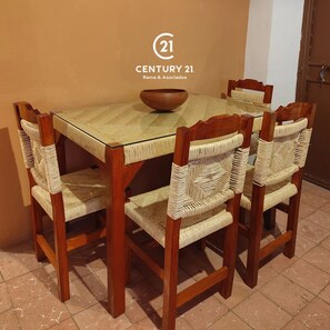 Une table à manger avec six chaises en bois, chacune dotée d’un siège en osier, et un plateau en verre.