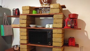 Een keuken met een ingebouwde magnetron en een plank voor een broodrooster, omringd door stapels bakstenen.