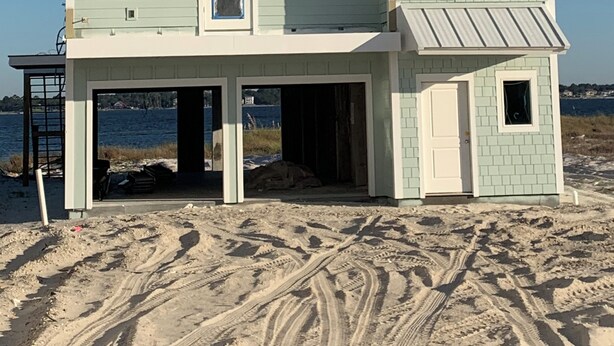 Ein mehrstöckiges Strandhaus mit flachem Dach und großen Fenstern.
