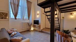 Una sala de estar moderna con un sofá, un televisor y una escalera que lleva a un nivel superior.