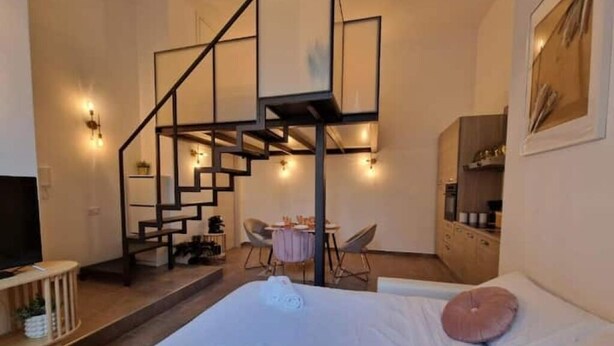 Un dormitorio con cama, escritorio, silla, escalera y televisor.