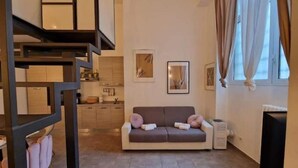 Una sala de estar moderna con un sofá, una escalera y una zona de cocina.