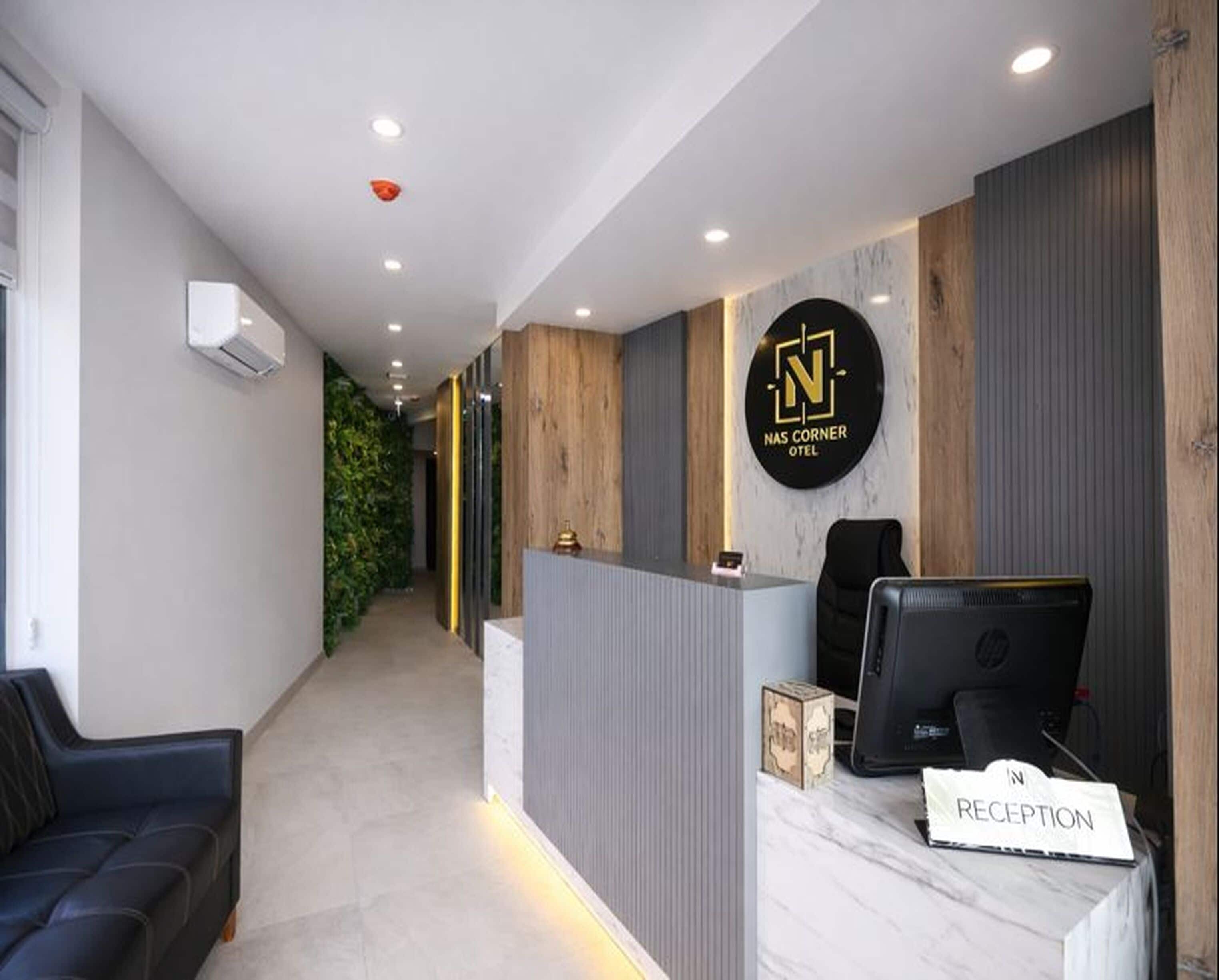 A reception area with a reception desk, a sign reading "NASC CORNER HOTEL," and a reception sign on the desk.