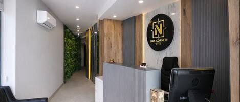 A reception area with a reception desk, a sign reading "NASC CORNER HOTEL," and a reception sign on the desk.