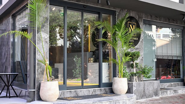 A modern hotel entrance with large glass doors, potted plants, and a visible sign for the Corner Hotel. - Nas Corner Hotel (Antalya)
