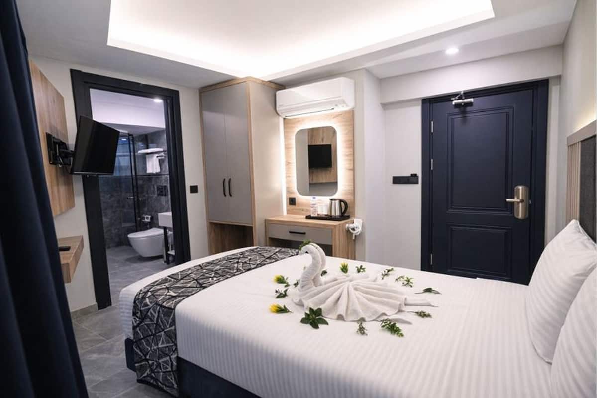 Una habitación de hotel con cama, baño, armario y puerta.
