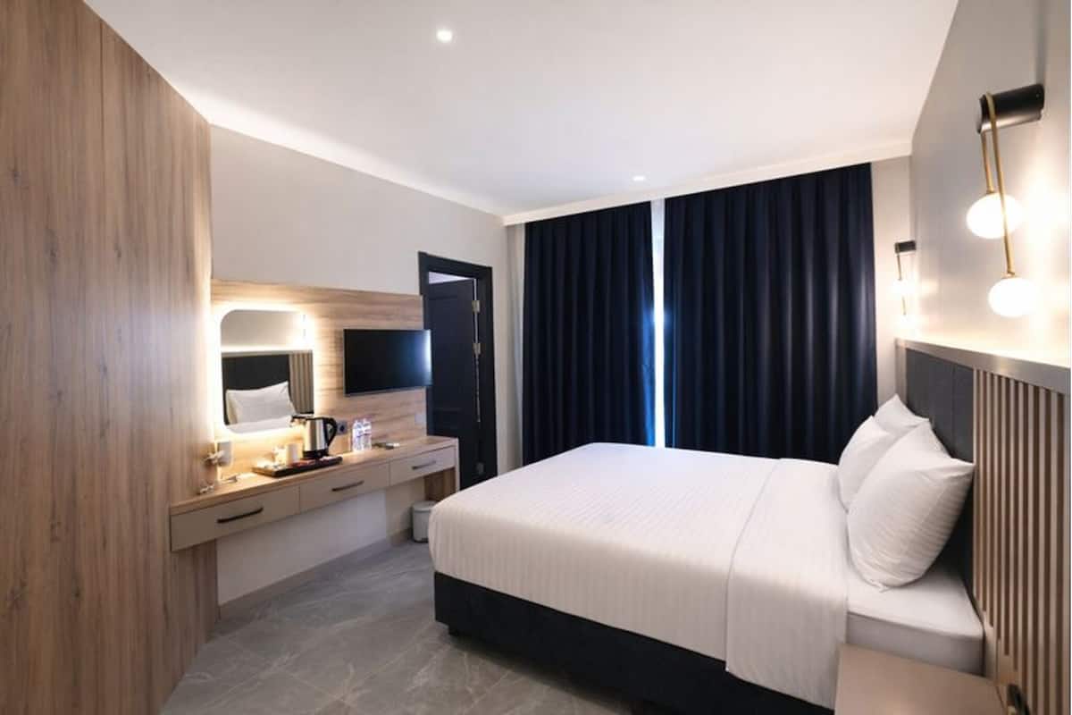 A modern hotel room with a bed, bedside table, mirror, and a TV.