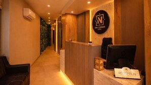 A reception area with a wooden reception desk, a computer, and a sign that reads "RECEPTION". - Nas Corner Hotel (Antalya)