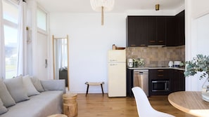 Eine moderne Küche mit dunklen Schränken, einem weißen Kühlschrank und einem Holztisch.