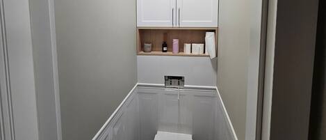 A narrow bathroom with a toilet, bidet, and storage cabinet.