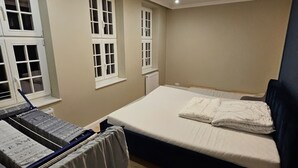 Une chambre à coucher avec un lit, une fenêtre, un radiateur et un luminaire au plafond.