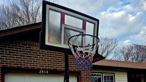Un garage attenant à une maison, avec un panier de basketball installé devant.