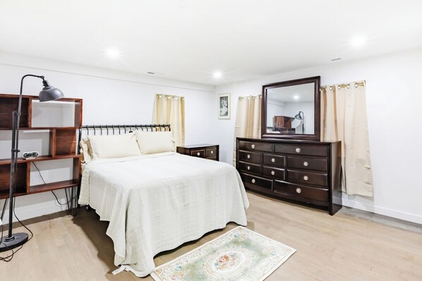 A bedroom with a bed, a dresser, a nightstand, a lamp, and a bookshelf. - Fresh 2BR Duplex Pets Welcome (Orange)