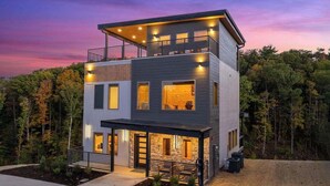 Ein modernes, zweistöckiges Haus mit Balkon, großen Fenstern und einem gut beleuchteten Eingangsbereich.