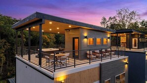 Ein modernes, mehrgeschossiges Haus mit überdachter Terrasse, Essbereich und Kamin.