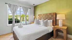 Een net opgemaakt bed met wit beddengoed, een houten hoofdbord en een nachtkastje met een lamp.