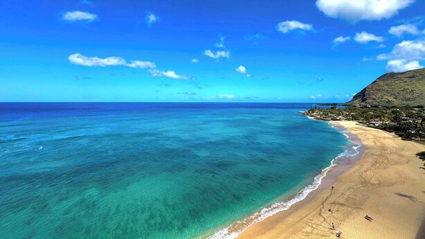 A beach with clear turquoise waters, a sandy shore, and a hilly backdrop. - Marbella Lane -  Beachfront  Haven w/ MT Views! (Waianae)