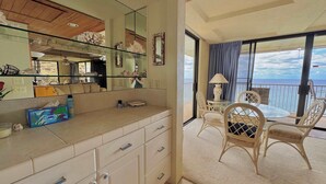 A hotel room with a balcony, a glass shower enclosure, a beige vanity with drawers, and a view of the sea. - Marbella Lane -  Beachfront  Haven w/ MT Views! (Waianae)