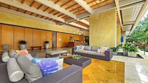 A spacious lobby with a modern design, featuring sofas, a coffee table, and potted plants. - Marbella Lane- Prime Watermark Ocean & City View (Honolulu)
