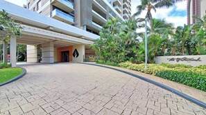 A hotel entrance with a covered walkway, palm trees, and a sign reading "The Waterfront." - Marbella Lane- Prime Watermark Ocean & City View (Honolulu)