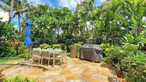A patio area with a stone floor, a table with chairs, and a grill. - Marbella Lane- Prime Watermark Ocean & City View (Honolulu)