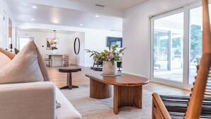Una sala moderna con un sofá, una mesa de centro y vistas al exterior a través de grandes ventanas.