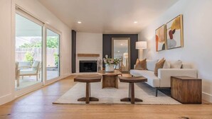 Una sala de estar moderna con chimenea, un juego de sofá y un comedor con dos mesas de madera.