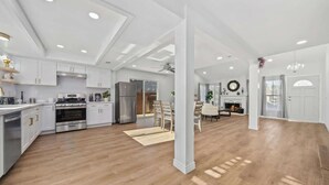 Une cuisine spacieuse avec des armoires blanches, des appareils en acier inoxydable et un plancher en bois.