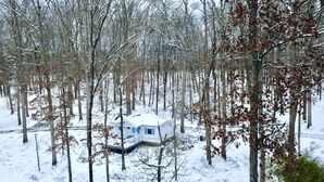 A cabin in a snowy forest with a snow-covered roof and a small porch.