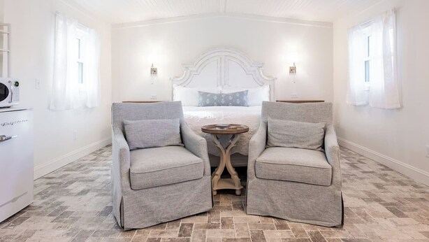A room with a bed, two armchairs, a small table, and a microwave.