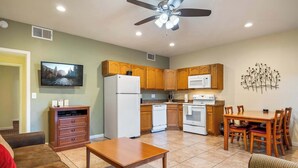 A compact living space with a kitchenette, a dining area, a TV mounted on the wall, and a ceiling fan. - Pine-Grand Canyon by Roundhouse Resort and Spa (Pinetop Country Club)