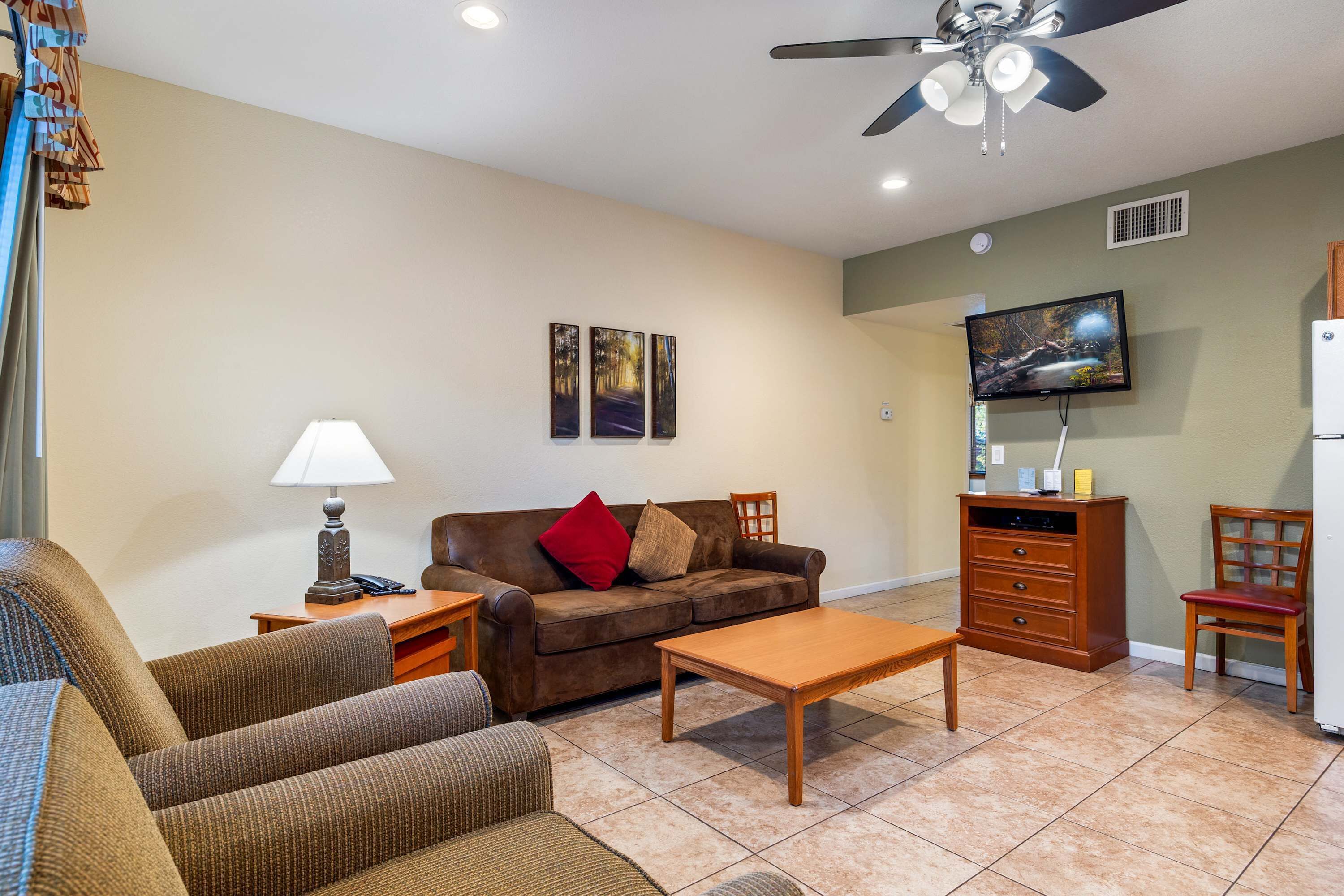 A living room with a brown sofa, a wooden coffee table, a TV, and a ceiling fan.