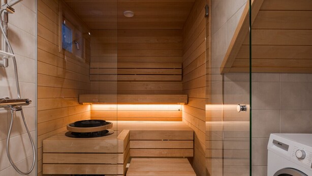 Eine Sauna mit Holzbänken, einer Waschmaschine und einer Duschkabine aus Glas.