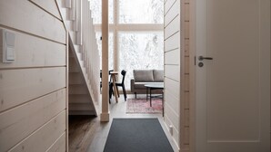 Ein Holzinnenraum mit einer Treppe, die zu einem Wohnbereich führt, einer Couch und einem kleinen Tisch.