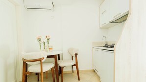 A small kitchen with white cabinets, a sink, and a dining area with two chairs and a small table. - Yellow 1-bedroom apartment with AC in vibrant Budva (Budva)
