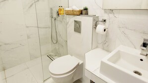 A modern bathroom with a glass-enclosed shower, a toilet, and a sink. - Yellow 1-bedroom apartment with AC in vibrant Budva (Budva)